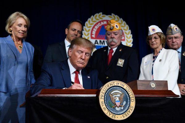 President Donald Trump signs a memorandum on veterans' student loan debt following his speech at the AMVETS 75th National Convention in Louisville, Ky., on Aug. 21, 2019. (Susan Walsh/AP)